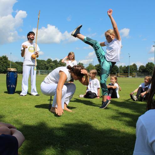 Hier siehst du Kinder, die Capoeira machen.