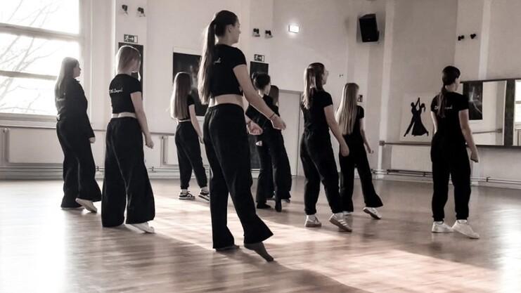 Hier siehst du unsere Tänzerinnen. Sie sind schwarz gekleidet und stehen in einer Formation hintereinander.