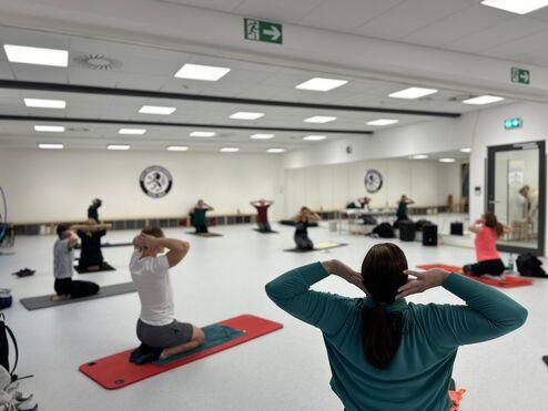 Hier siehst du einen Einblick in einen unserer Kurse. Die Teilnehmenden knien und haben die H&auml;nde hinter dem Kopf.