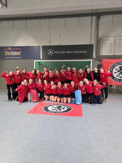 Hier siehst du zwei Hockey-Teams in roten Trikots.