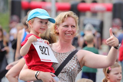 Hier siehst du eine Mutter mit ihrem Sohn und der Sohn hält eine Startnummer in die Luft.