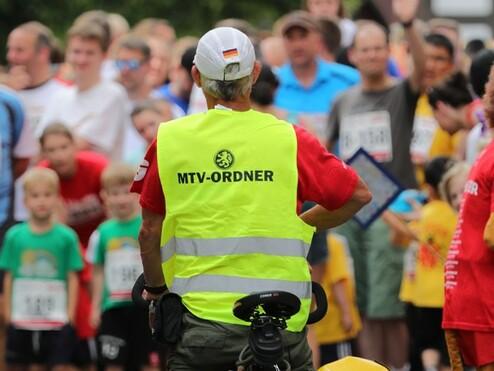 Hier siehst du einen Radbegleiter beim Nachtlauf. Er hat eine gelbe Warnweste an.