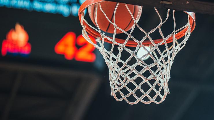 Basketballkorb mit Ball, der im Netz steckt, im Vordergrund; im Hintergrund ist die Punktzahl 42 zu sehen.