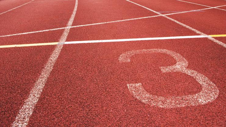 Nahaufnahme eines roten Laufbahnabschnitts mit der Markierung der Bahn 3 und weißen Linien.